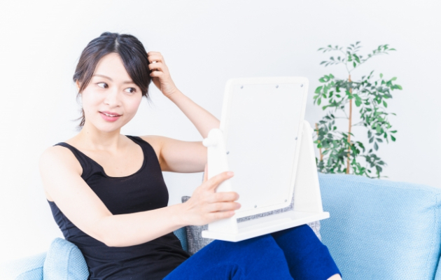 頭皮アートメイクの施術効果を鏡で実感する女性